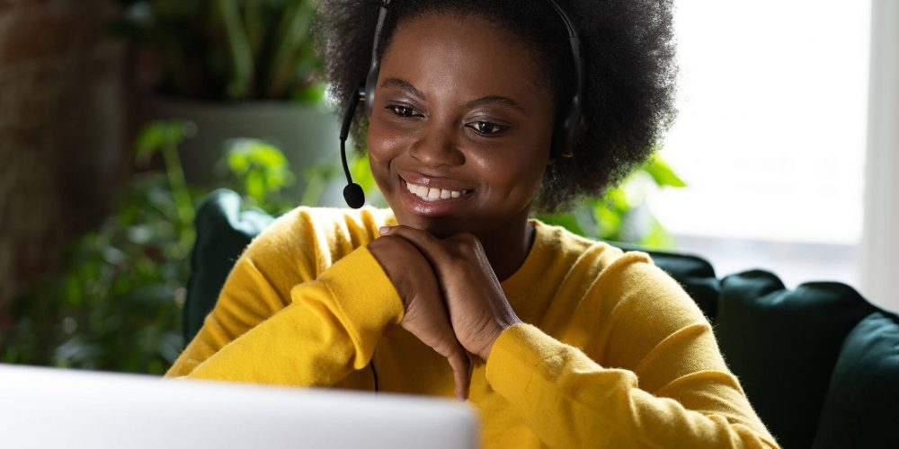 smiling-afro-woman-wear-headphones-talk-video-calling-using-laptop-watching-webinar-work-from-home
